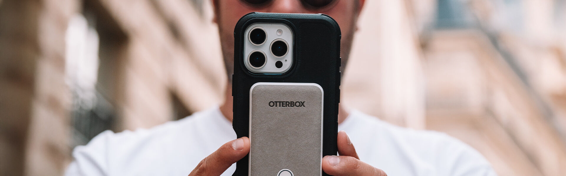 Person holding a phone with a OneBox case against a blurred background