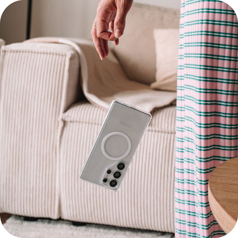 Smartphone being dropped in front of a beige sofa